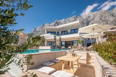 an outdoor dining area next to a swimming pool with mountains in the backgroud