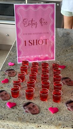 a table topped with lots of cups filled with red liquid and pink hearts on top of it