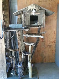 a bird house made out of driftwood in a room with wood walls and flooring