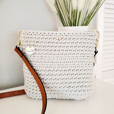 This charming boho crossbody bag is petite yet roomy.  It's just the right size to hold your everyday essentials for a fuss-free day out.  It is lightweight at 15 ounces empty, with a perfect adjustable leather strap. Lovingly crocheted by hand, this bag is one of a kind. Whether you're stepping out for a casual outing or headed to a chic brunch, this small crossbody bag is ready to compliment any outfit with charm.  This bag is extremely durable and eco-friendly, crocheted with 100% recycled 5mm cotton cord.  The brown leather strap is adjustable and the bag includes a magnetic snap closure.   COLORS This beautiful crossbody bag is available in beige with adjustable brown leather strap.  MEASUREMENTS 8 INCHES HIGH 8 INCHES WIDE STRAP  IS ADJUSTABLE from 43 inches to 51 inches in length MA Small Crochet Purse, Crocheted Gifts, Boho Crossbody Bag, Small Crochet, Crochet Purse, Ladies Handbags, Brown Leather Strap, Boho Bag, Crochet Purses