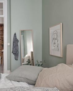 a bedroom with a bed, mirror and pictures hanging on the wall in front of it