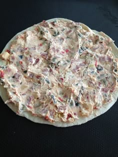 an uncooked pizza sitting on top of a black table next to a knife