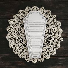 a white doily with a paper tag attached to it on a wooden table top