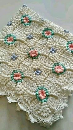 a crocheted doily with flowers on it sitting on top of a table