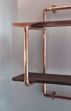 the shelves are made out of metal pipes and wooden brackets on each side, along with copper piping