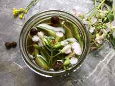 a glass jar filled with green beans and flowers on top of a table next to dried flowers