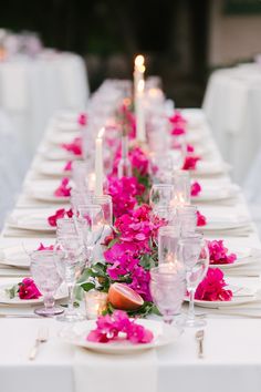 a long table is set with white linens and pink flowers on the runneres