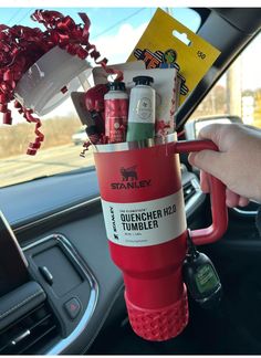 a person holding a cup filled with items in their car