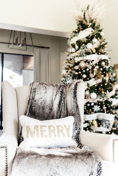 a black and white photo of a christmas tree in a living room next to a chair