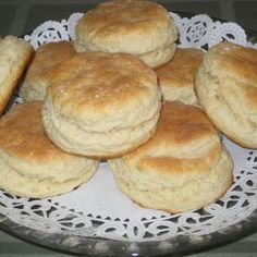 a plate full of biscuits sitting on top of a doily next to a glass bowl