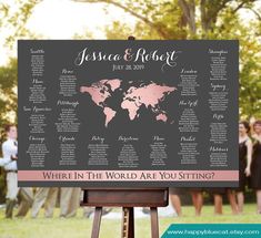 a wedding seating chart with pink and black world map on it, surrounded by people in the background