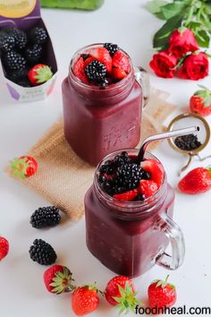 two mason jars filled with berries and raspberries on top of a white table