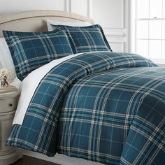 a bed with blue plaid comforter and pillows