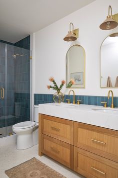 a bathroom with blue tile and wooden cabinets, two sinks, and a shower stall