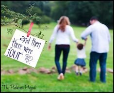 a man and woman holding hands while walking with a small child in a field behind them