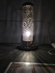 a lamp that is on top of a table with a light shining in the dark