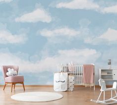 a baby's room with blue sky and clouds painted on the wall behind it