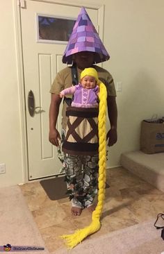 a man in a purple hat holding a baby wearing a yellow wig and braids