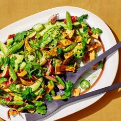 a white plate topped with salad and two serving utensils