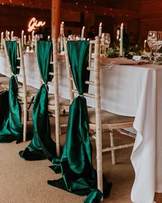 chairs with green sashes are lined up at the head table for a formal dinner