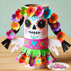 a paper cup decorated with colorful flowers and a skull on the top, sitting on a table