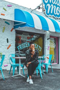 a woman sitting in front of a frozen treat shop