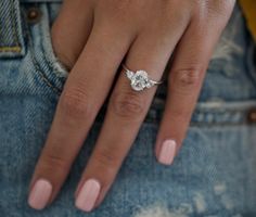 a close up of a person's hand with a diamond ring on their finger