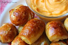 several rolls on a plate with a bowl of peanut butter in the middle and an orange dip in the background