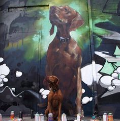 a brown dog sitting in front of a painting