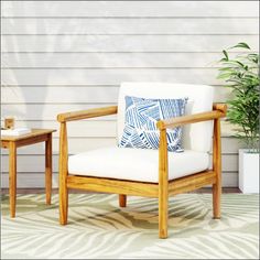 a chair and table sitting on top of a rug in front of a white house