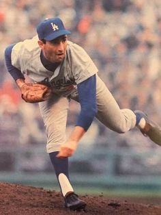 a baseball player pitching a ball on top of a field in front of a crowd