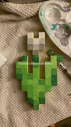 a piece of art made to look like a minecraft creeper with paintbrushes next to it