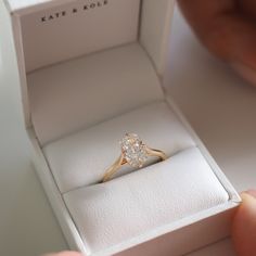 a person holding an engagement ring in a box