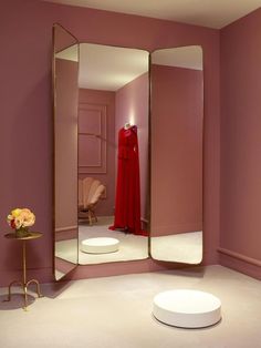 a pink room with a large mirror and mannequins in the corner,