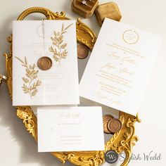 the wedding stationery is laid out on a gold plate with two pennons and one penny