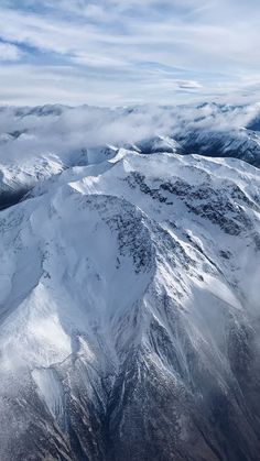 an aerial view of snow covered mountains and clouds