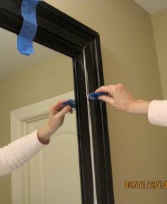 two women are brushing their teeth in front of a mirror with blue tape on it