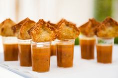 small cups filled with food sitting on top of a white table covered in sauces