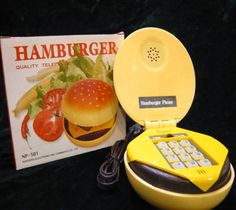 a yellow hamburger phone sitting next to a book on a black table with it's cover open