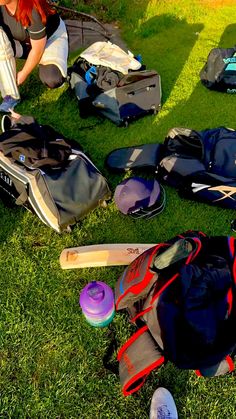 a woman sitting in the grass with her back pack and baseball bat on it's shoulder