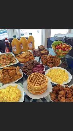 a table topped with lots of different types of breakfast foods next to orange juice and fruit