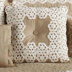 two decorative pillows on a bed with white lace and burlucks, one has a button in the middle