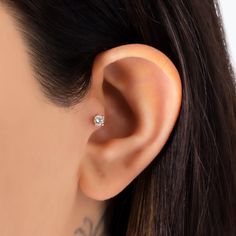 a woman wearing an ear piercing with a single diamond in it's right ear