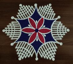 a red, white and blue flower on a wooden surface with beads in the middle