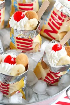 small ice cream sundaes with banana slices and cherries on top, in tin foil cups