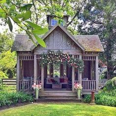 a small wooden gazebo with flowers on the front porch and steps leading up to it