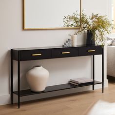 a white vase sitting on top of a wooden table next to a black and gold shelf