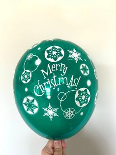 a person holding up a green christmas balloon