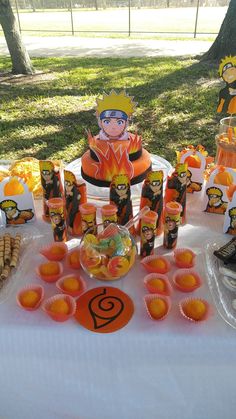 a table topped with cupcakes and cakes covered in frosting next to trees