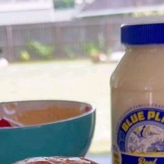 a bottle of blue plate mayonnaise next to a bowl of food on a table